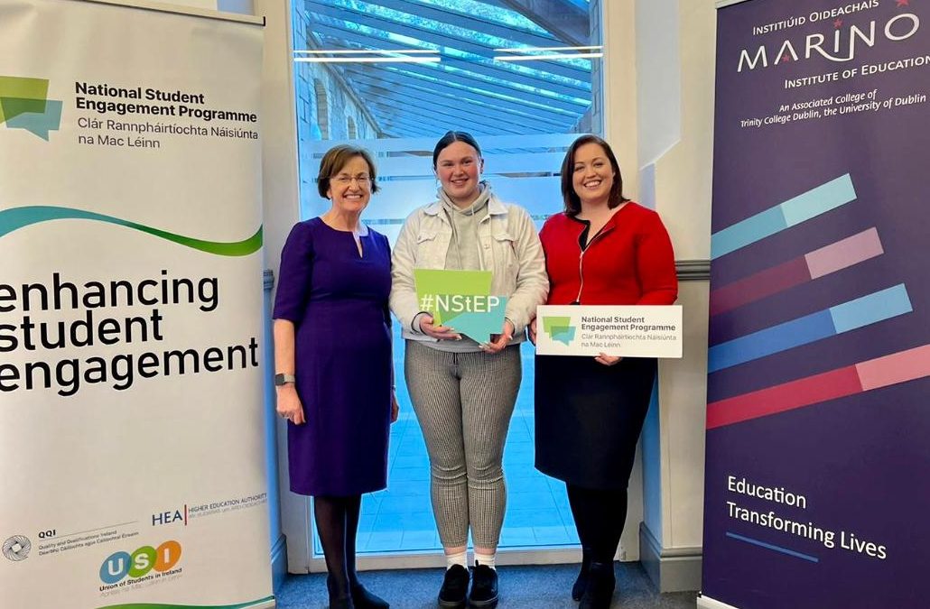 Image of 3 people - Teresa O'Doherty, Ellen O'Connell, and Aimie Brennan - smiling and standing in front of an NStEP banner and a Marino Institute banner.