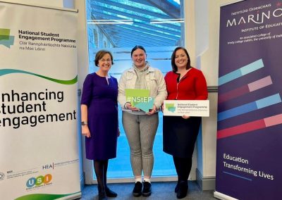 Image of 3 people - Teresa O'Doherty, Ellen O'Connell, and Aimie Brennan - smiling and standing in front of an NStEP banner and a Marino Institute banner.